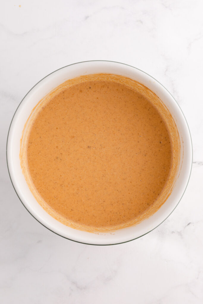 top down image showing a white bowl filled with pumpkin pie filling