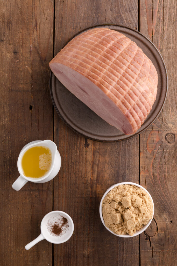 Top down image showing an uncooked ham with pineapple juice, brown sugar, and cloves