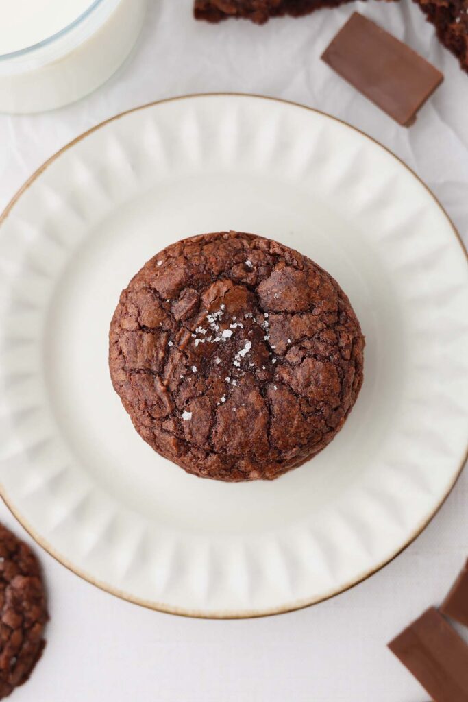 Top down image showing a chocolate crackle topped cookie on top of a white plate