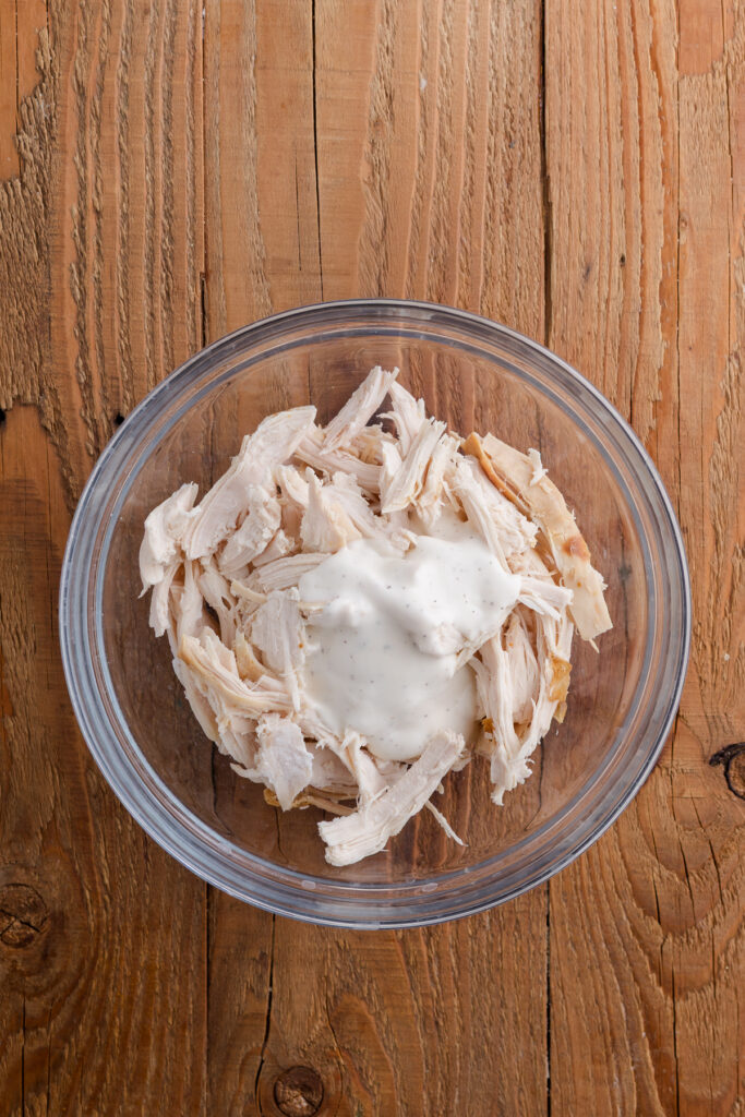 Shredded chicken with ranch dressing in a mixing bowl