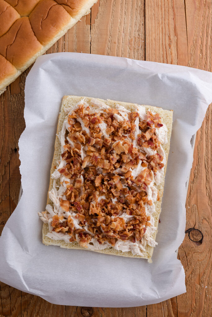 Cooked bacon sprinkled over the ranch chicken layer on slider rolls