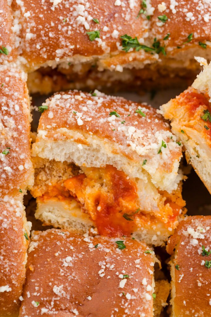 close up image showing sliders made with crispy chicken and red sauce sprinkled with parmesan