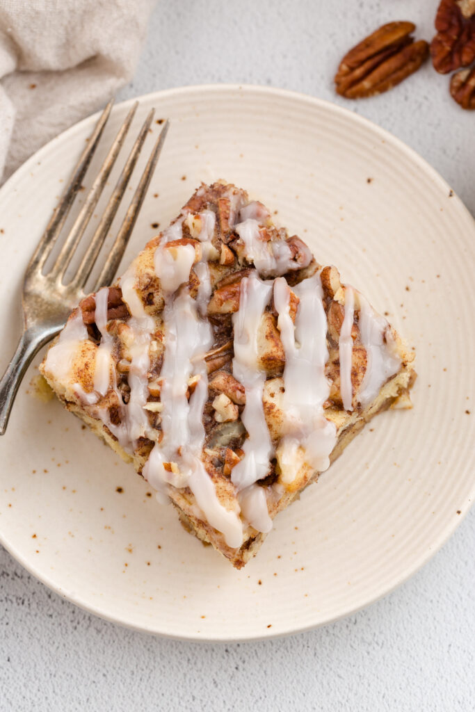 top down image showing a white plat ewith a square of cinnamon roll bake on top with a fork