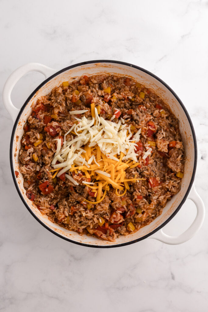 Cooked beef and rice topped with shredded cheddar and mozzarella cheeses before baking or melting.