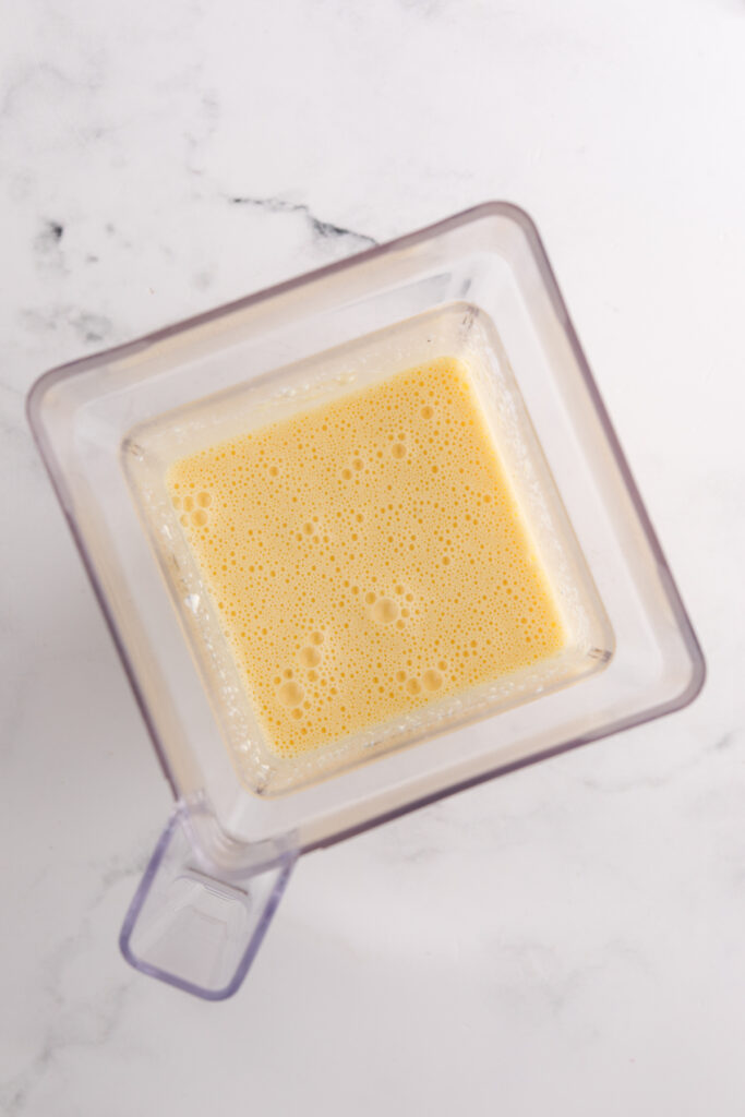 top down image showing the inside of a blender with cheese, eggs, cottage cheese, ranch seasoning blended