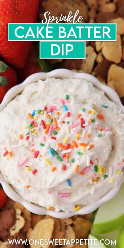 Creamy birthday cake dip topped with rainbow sprinkles in a white bowl, surrounded by fresh strawberries, green apple slices, and assorted animal crackers on a dessert boa