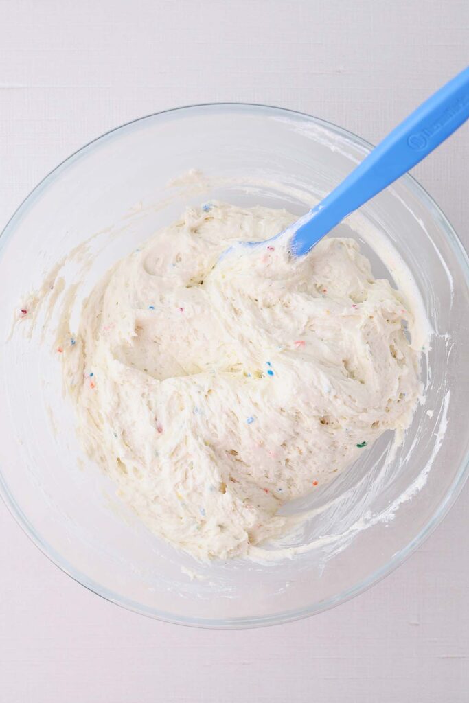 top down image showing cake mix being stirred with a blue spoon with whipped topping