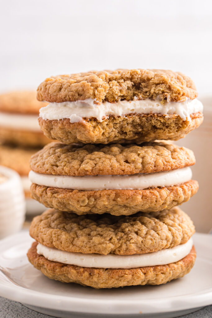 close up image showing an oatmeal cream pie stacked on a plate with more cookies