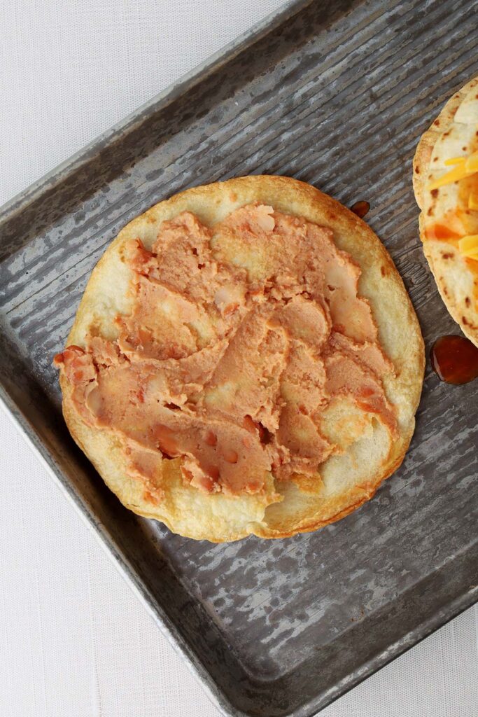 Top down image showing a crispy baked tortilla spread with refried beans