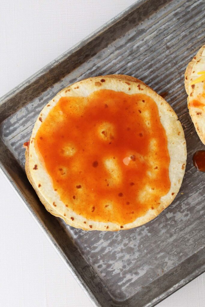 Top down image showing a crispy baked tortilla spread with enchilada sauce