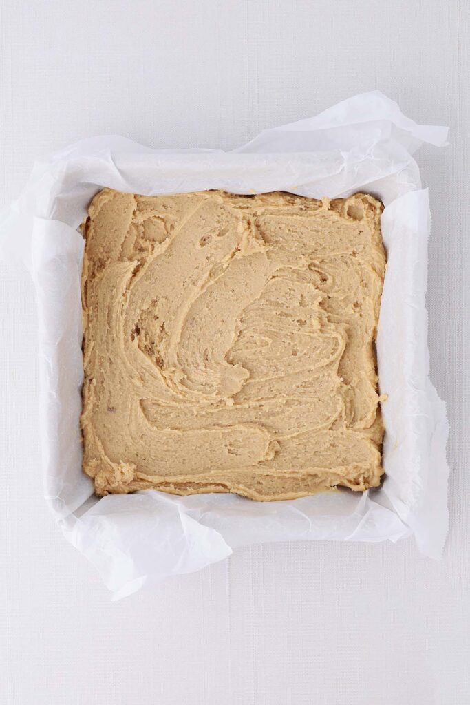 top down image showing a parchment lined pan with dough pressed into the bottom