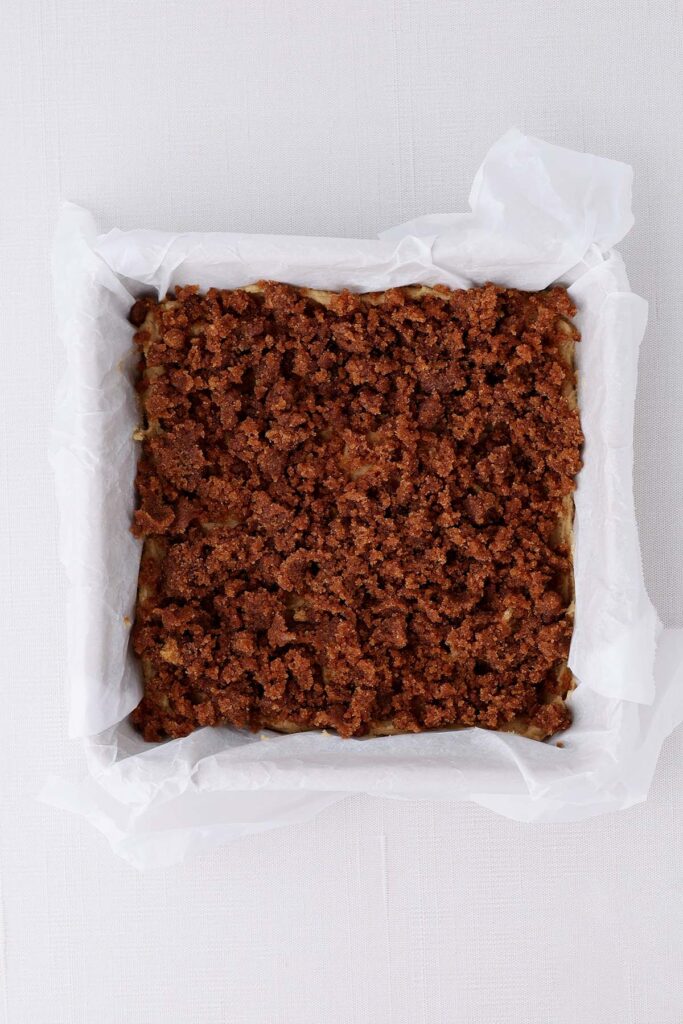 top down image showing a parchment lined pan with a cinnamon crumb mixture