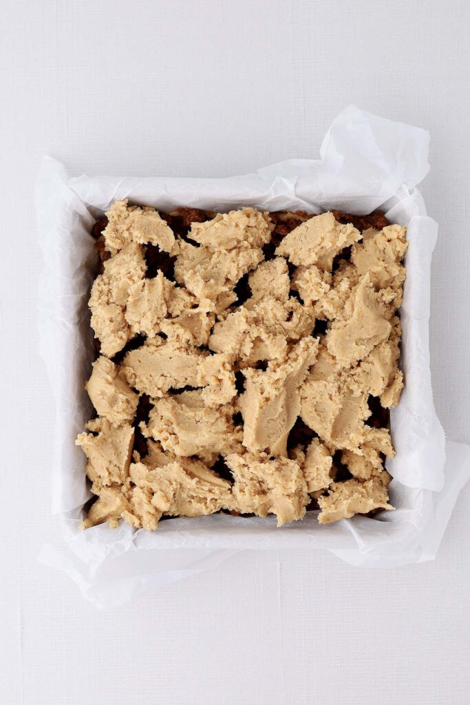 top down image showing a parchment lined pan with dough dotted on top
