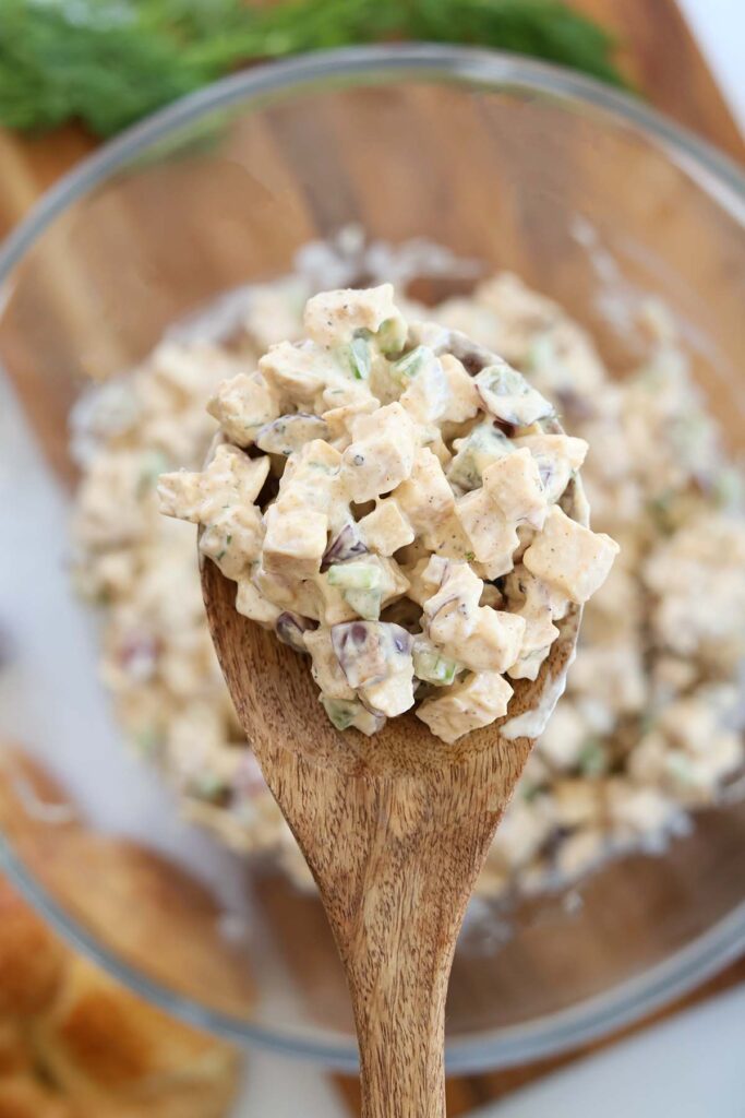 close up image showing chicken salad scooped onto a wooden kitchen spoon