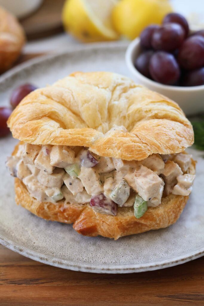 Clos up image showing a croissant that is sliced in half and filled with chicken salad