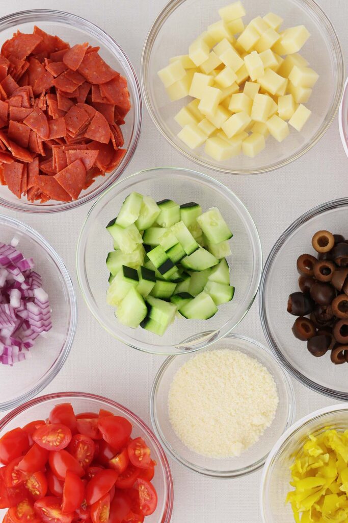 Top down image sowing small glass bowls filled wiht vegetables and cheeses for pasta salad