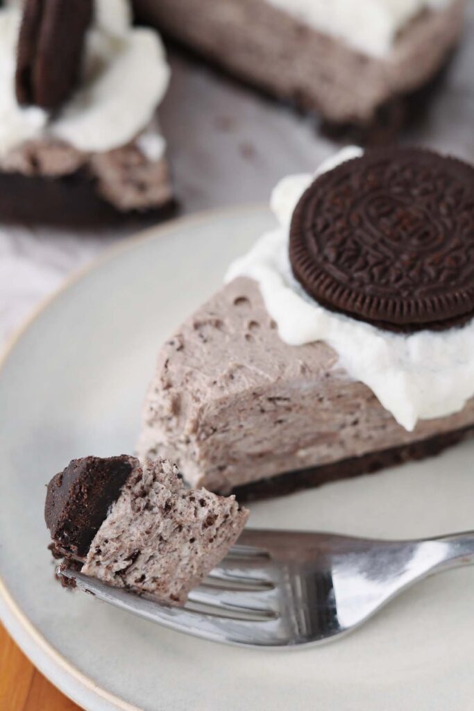 close up image showing a white plate with a slice of cheesecake and a bite on a fork