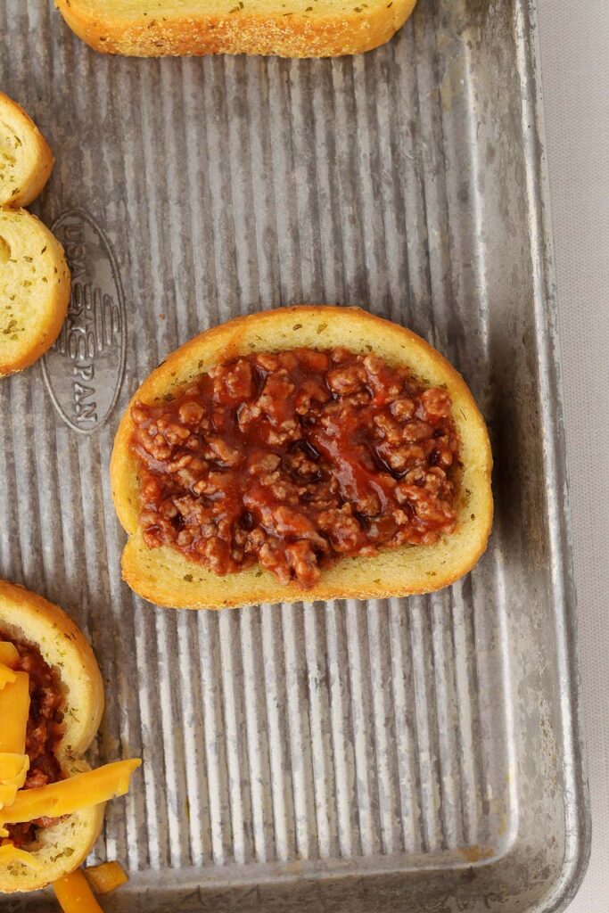 Top down image showing a baked garlic toast with the center pressed down and filled with a saucy beef mixture