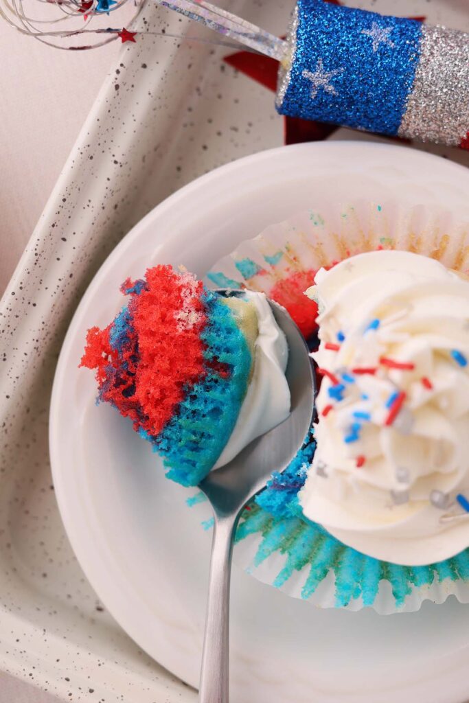 close up showing a cupcake with a bite on a spoon. Bright red white and blue colors