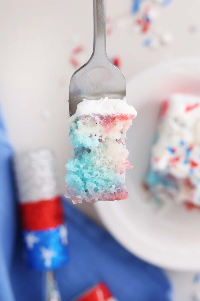 close up image showing a bite of red white and blue cake on a fork
