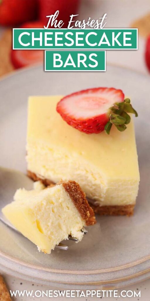 Close-up of a homemade cheesecake bar with a buttery graham cracker crust and smooth, creamy filling, garnished with a sliced strawberry and served on a gray dessert plate.