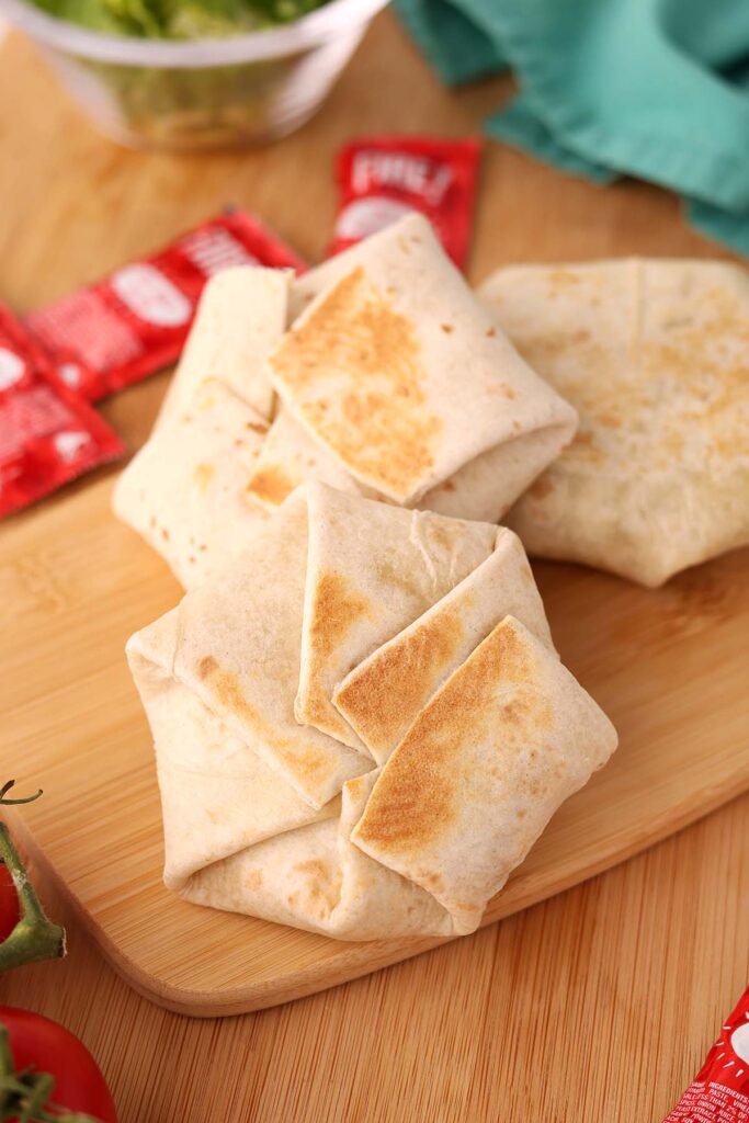 close up image showing three small folded and grilled tortillas on a wooden table top