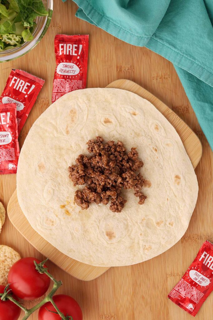 Top down image showing a tortilla with a pile of taco meat in the middle