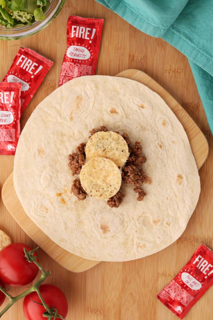 Top down image showing a tortilla with a pile of taco meat in the middle with two tortilla chips