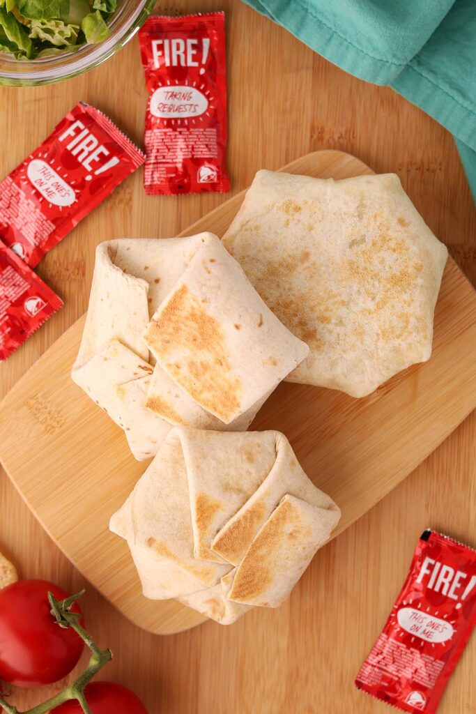 close up image showing three small folded and grilled tortillas on a wooden table top