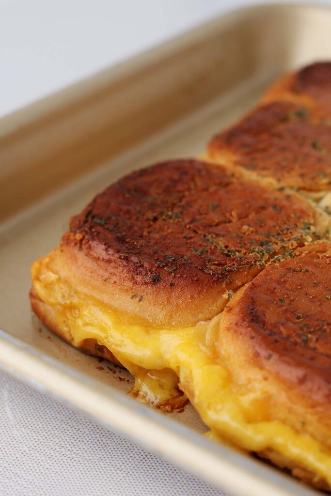 Close up image showing a slider on a pan with cheese melting out the sides