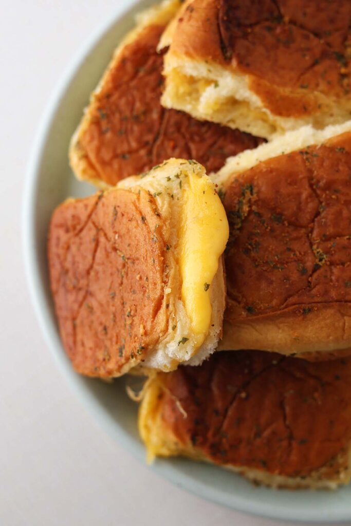 Top down image showing a light blue plat stacked with mini grilled cheese sandwiches