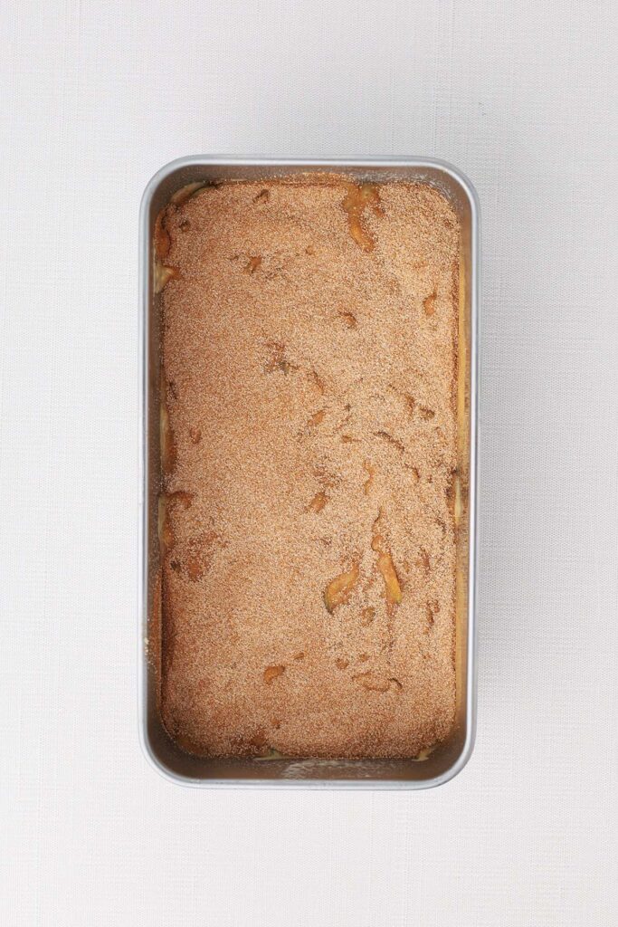 Top down image showing a bread tin filled with a zucchini batter covered with cinnamon ugar