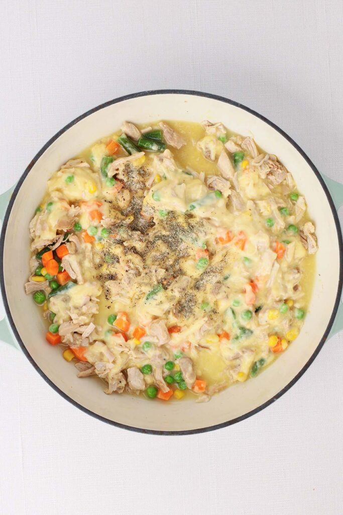 Top down image showing the inside of a skillet with cream of chicken soup, mixed veggies, chicken that's cooked and shredded and chicken broth mixed