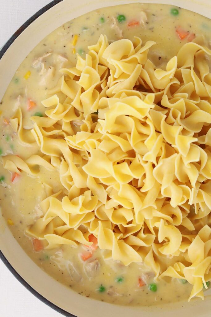 Top down image showing cooked pasta noodles sitting on top of a creamy sauce