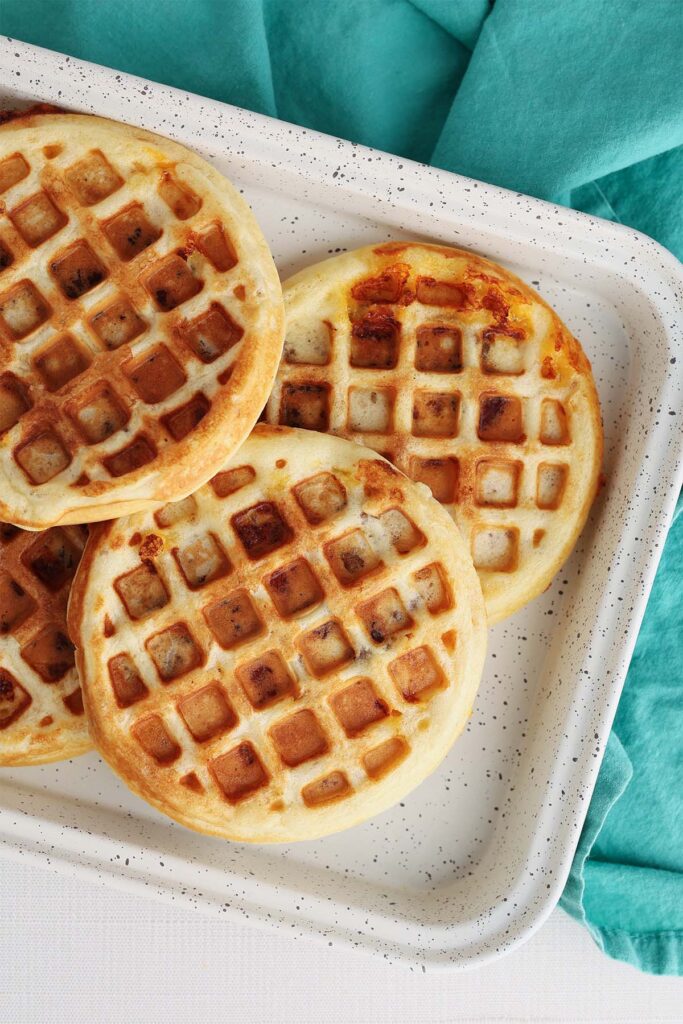 Top down image showing a white speckled tray with a stack of golden waffles